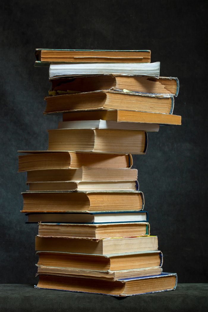 Mastering the First Impression: Your intriguing post title goes here A towering stack of vintage books with weathered pages on a dark, textured background.